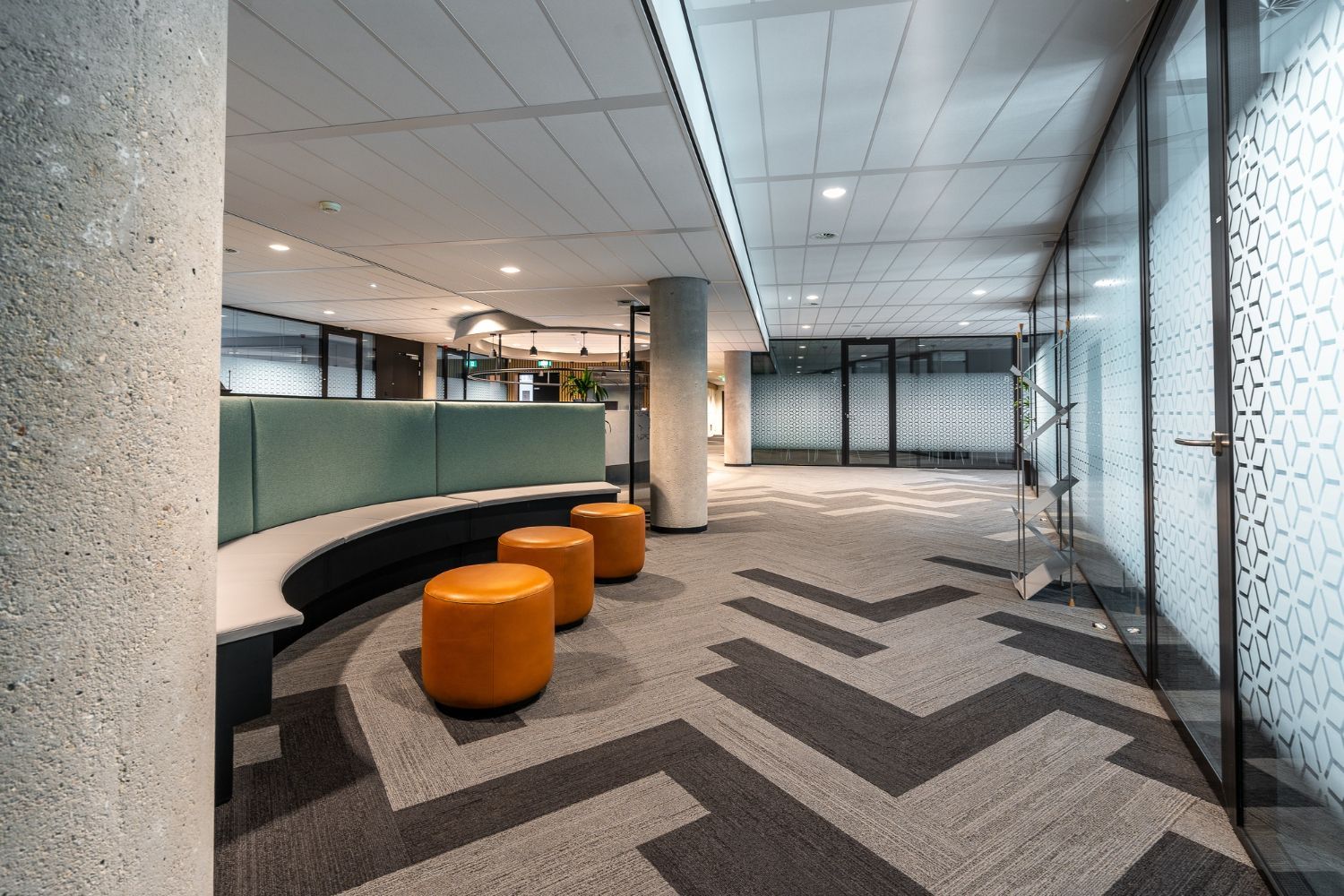 Commercial office lounge with gray herringbone carpet tile and orange seating